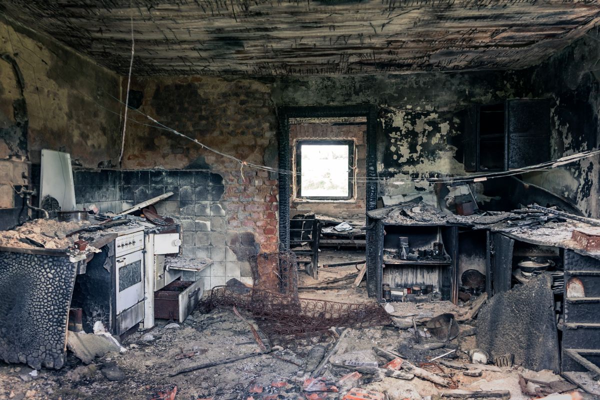 Fire and smoke damaged interior of a home with charred walls and soot