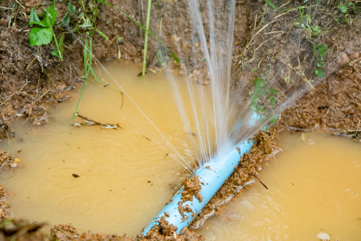 Burst supply pipe spraying water at a failed joint — the kind of sudden leak that floods Tucson homes