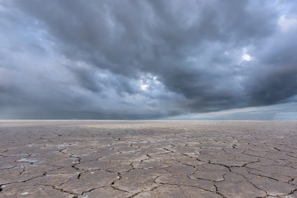 Storm clouds building over cracked desert ground ahead of a flash flood