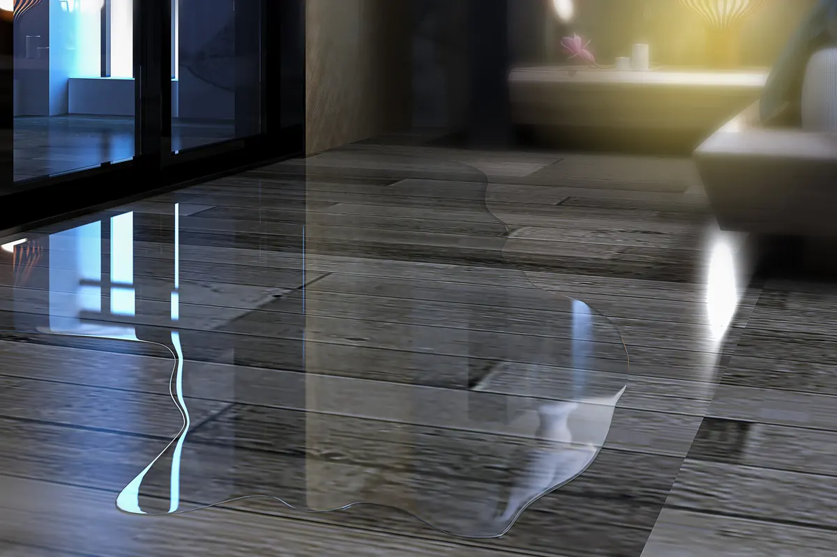 Water pooling across a parquet wood floor before mitigation and structural drying