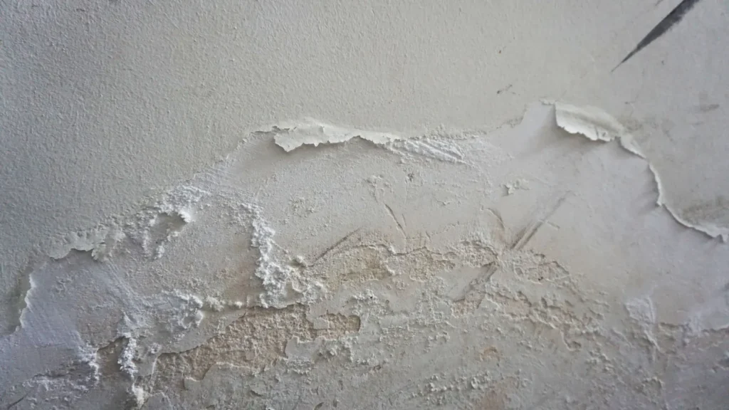 Interior wall with paint bubbling and swelling from moisture behind it, the classic sign of drywall water damage in Tucson homes