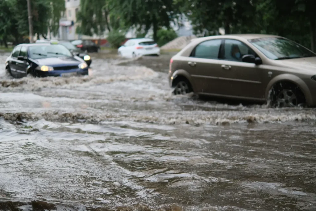 Cars pushing through a flooded intersection during an Arizona monsoon storm — Goodyear’s flat ag-conversion land drains slowly when cells stall
