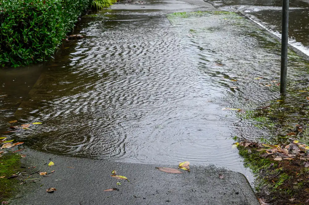 Storm water sheeting across a neighborhood street after a monsoon downpour — Glendale’s west-side channels carry Skunk Creek and New River flows