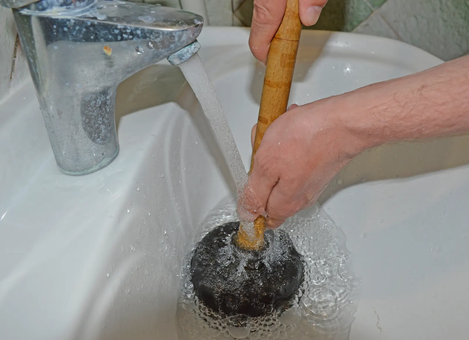Homeowner attempting to clear a backed-up drain before calling for sewage cleanup in Vail, AZ