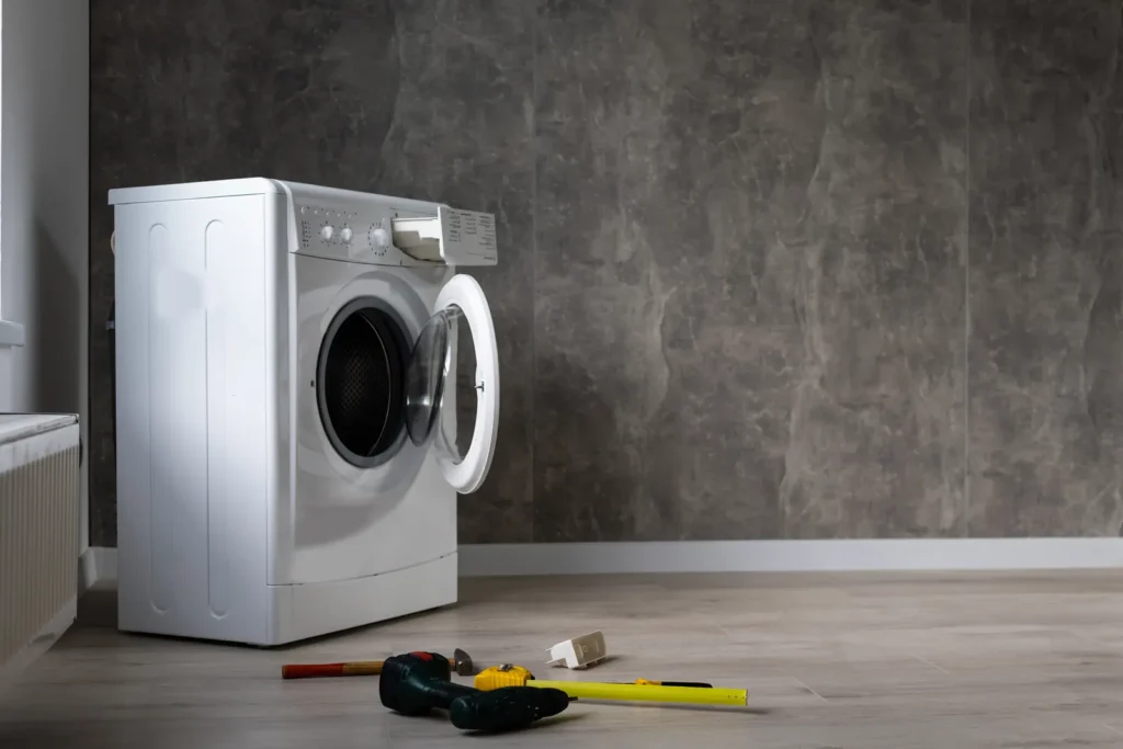 Washing machine overflowing across a laundry-room floor — in Buckeye’s 2000s-built subdivisions, original supply hoses and angle stops are aging out together on some of the hardest water in the Phoenix metro